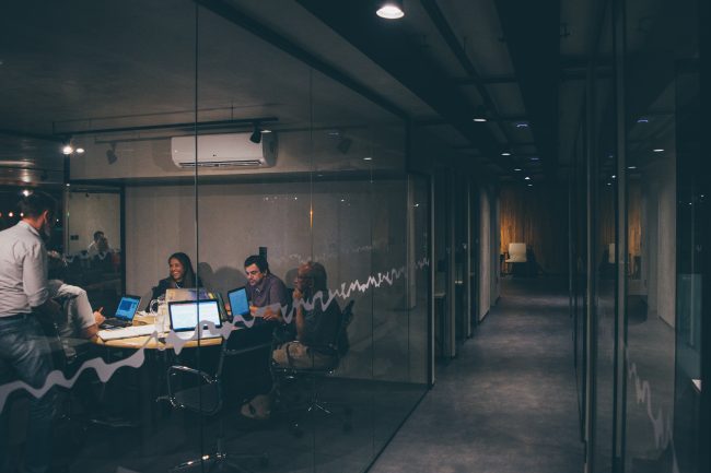 People working on computers in office behind glass window